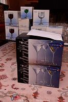 Boxes of Claudia Bohemian Crystal glassware of different types stacked with two boxes of Luminarc martini glasses in front.