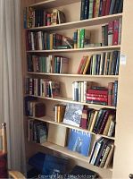 Full view of seven shelves filled with numerous hardcover books of various colors and sizes, showing arrangement and quantity