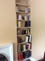 Shelf with seven shelves containing books, some DVDs and VHS tapes.