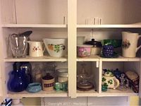 Overall view of multiple kitchen items on shelves including pitchers, bowls, teapots and containers of various materials and colors