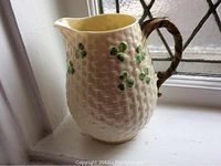 Side view of the pitcher showing the basket-weave texture and shamrock motifs with the handle visible.