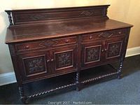 Full frontal view of the wooden carved buffet sideboard showing detailed carved designs on drawers and cabinet doors, with twisted spindle legs and stretchers.
