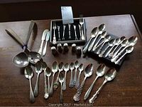 Overhead view of entire lot showing spoons, salt shakers, serving utensils, butter knives, and box of cocktail forks