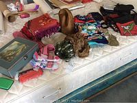 Photo showing collection of scarves with various patterns, brown vintage hat, and some purses on mattress.