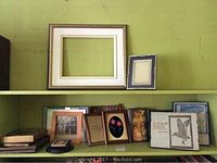 Various picture frames and small art pieces displayed on shelves including empty frames and framed prints.