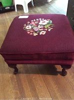 Top view of the burgundy needlepoint fabric ottoman with central floral needlepoint design.
