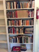 Wide view of six shelves filled with assorted books of various sizes and colors.