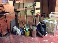 Overall view of lot with shovels, fans, dolly, cleaning supplies, golf bag, and metal drawer rack in basement