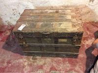 Front and top view of the old trunk showing worn wooden surfaces and metal bands.