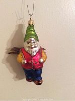 Front-side view showing the detailed hand painted facial features, green hat, red vest, yellow shirt, and blue pants.