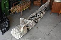 Rolled carpet on concrete floor with furniture in background