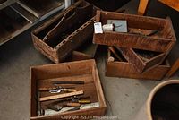 Photo showing six various vintage wooden boxes containing assorted vintage hand tools such as hammers, pliers, wooden ruler, and others.