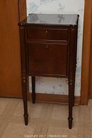 Front view of the Bombay side table showing drawer and cabinet door with keyholes, barley twist legs, and wood inlay top surface.