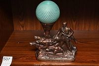 Full view of vintage bronze lamp with glass ball shade showing hunter and dogs