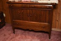 Full view of vintage wooden sideboard showing wood grain, rounded wooden knobs on drawers and doors, and caster wheels on legs.