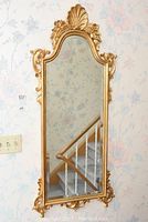 Full view of the tall hallway mirror showing the entire ornate gold frame and reflection of staircase.