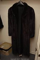 Full-length front view of coat hanging on a black hanger in a closet