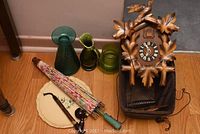 Overview of clock, glassware, umbrella, pipes, and plate on wooden floor.