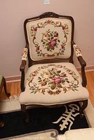 Front view of chair showing full needlepoint upholstery and carved wood frame