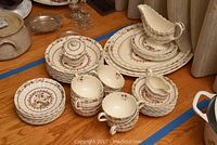 Full view of the Spode Aspire dish set including various plates, cups, and serving items on wooden floor.