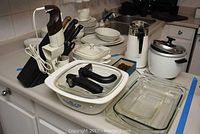 Overview of all lot items on countertop: bakeware, appliances, blender, knives