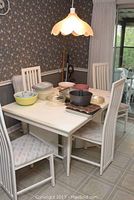 Full view of white dining table with four matching chairs in dining area
