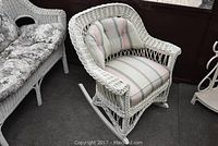 Full view of the white wicker rocker chair showing the striped cushioned seat and back