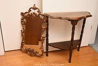 Both demi lune table and ornate mirror shown together on floor, seen clearly with details of table legs and mirror frame