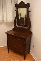 Full front view of tiger oak dresser with attached mirror showing three drawers and carved crest