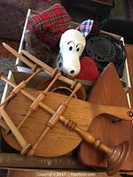 Top view showing a pile of wood cutting boards, a white Snoopy container, iron trivets, and wood decor items packed together.