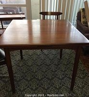 Full view of teak dining table with leaves closed