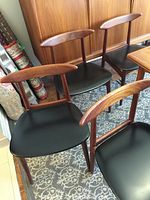 Four teak dining chairs grouped together, showing overall style and condition