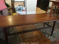 Front angle view of rectangular teak coffee table showing wood grain top and tapered legs