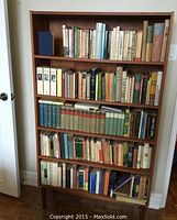 Full view of wooden bookcase filled with older books on five shelves.