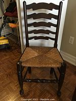 Front view of solid wood chair with ladder back and woven rush seat showing minor wear.