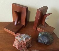 Pair of solid teak bookends with two natural decorative stones on wooden surface.