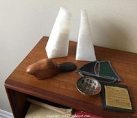 Photo showing set of white alabaster bookends, hand carved wooden beaver, stained glass ship, and small pottery dish on wooden surface.