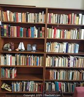 Full view of the wooden bookcase filled with a variety of older books, showing the size and condition of the bookcase and books.