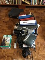 Full overview of the lot showing Olympia typewriter base, assorted notepads, envelopes, record books, GE answering machine, clock radio, cables, and VTech cordless phone box.