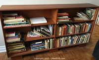 Front view of the wooden bookcase filled with assorted books on all shelves.