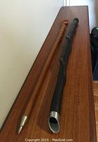 Two walking sticks laid side by side on wooden surface showing length and overall shape.