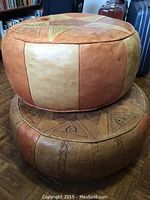 Two round leather hassocks stacked, showing patchwork panels