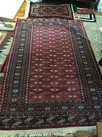 Full view of the larger rug laid on the floor showing complete pattern and size relative to surroundings, including smaller rug folded in the corner.