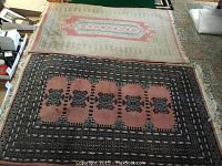 View of both rugs laid out side by side on carpeted floor showing full patterns and wear