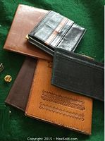Assorted leather wallets, cardholders and a gold-tone cufflink displayed on green background