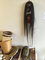 View of the two wood masks hanging on the wall, clay mask and carvings placed on a box below