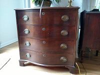 Front full view of mahogany chest showing four curved drawers with oval drawer pulls and keyhole locks