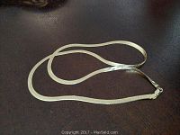 Full view of gold chain laid out on dark surface