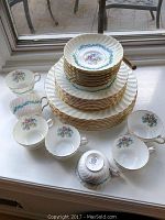 Full set arranged on a surface showing stack of plates (dinner, salad, soup) and 7 cups arrayed around them.