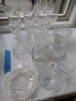 Collection of wine glasses and crystal bowls displayed on windowsill